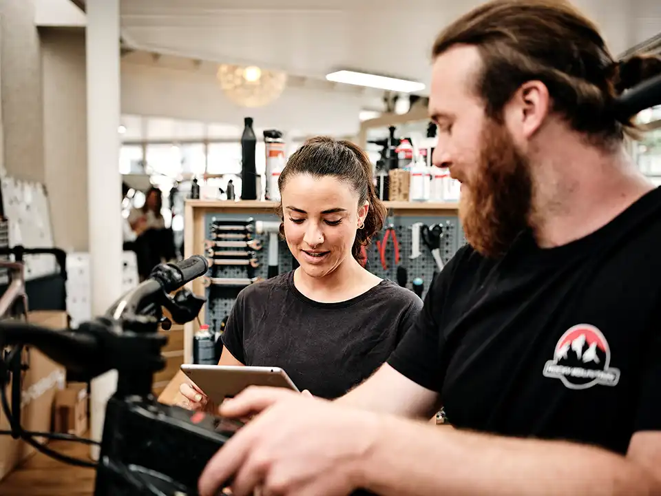 Ein Dienstrad wird im Fachhandel gservicet, die mechanikerin liest die Liste am Tablet ab